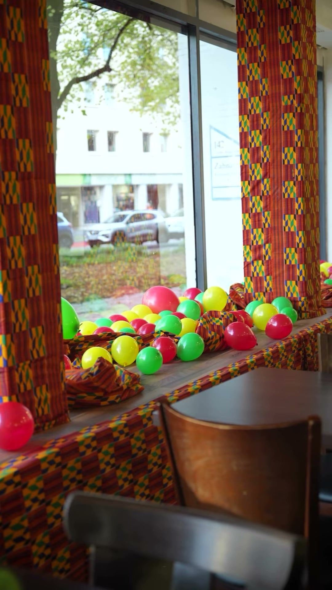 Fenster mit Vorhängen aus Kente-Stoff und bunten Ballons